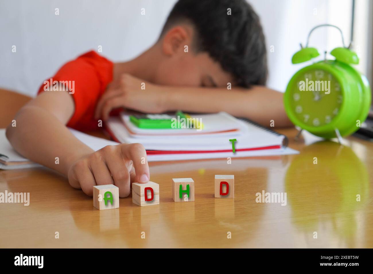 Enfant entouré de livres et de cahiers frustré, avec l'acronyme ADHD, représente la maladie trouble déficit de l'attention et les difficultés qu'il e Banque D'Images