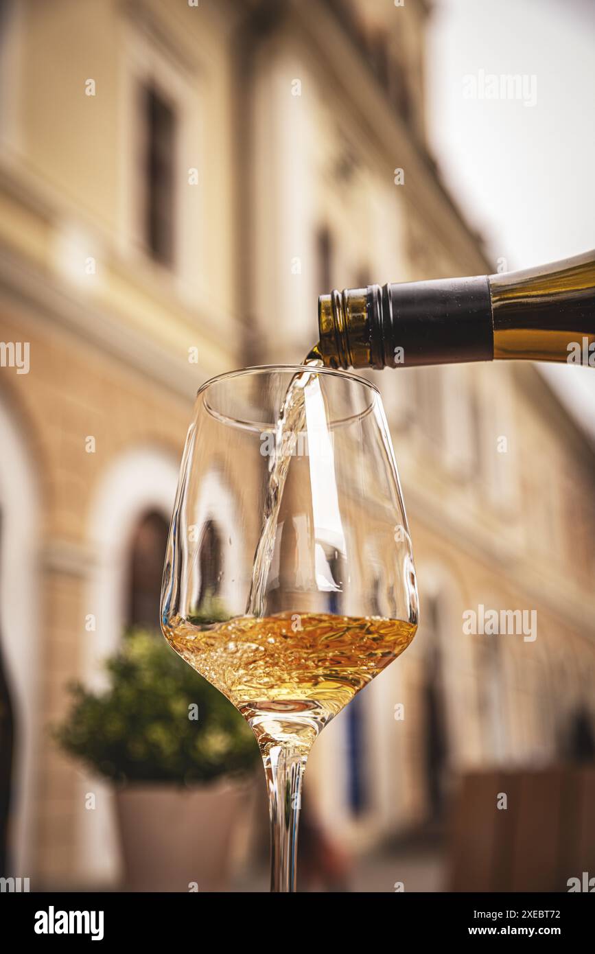 Un verre de vin blanc est versé sur une table en bois d'un restaurant en plein air Banque D'Images