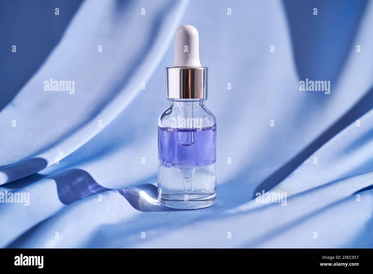 Sérum facial à deux composants sur fond de soie bleue. Banque D'Images