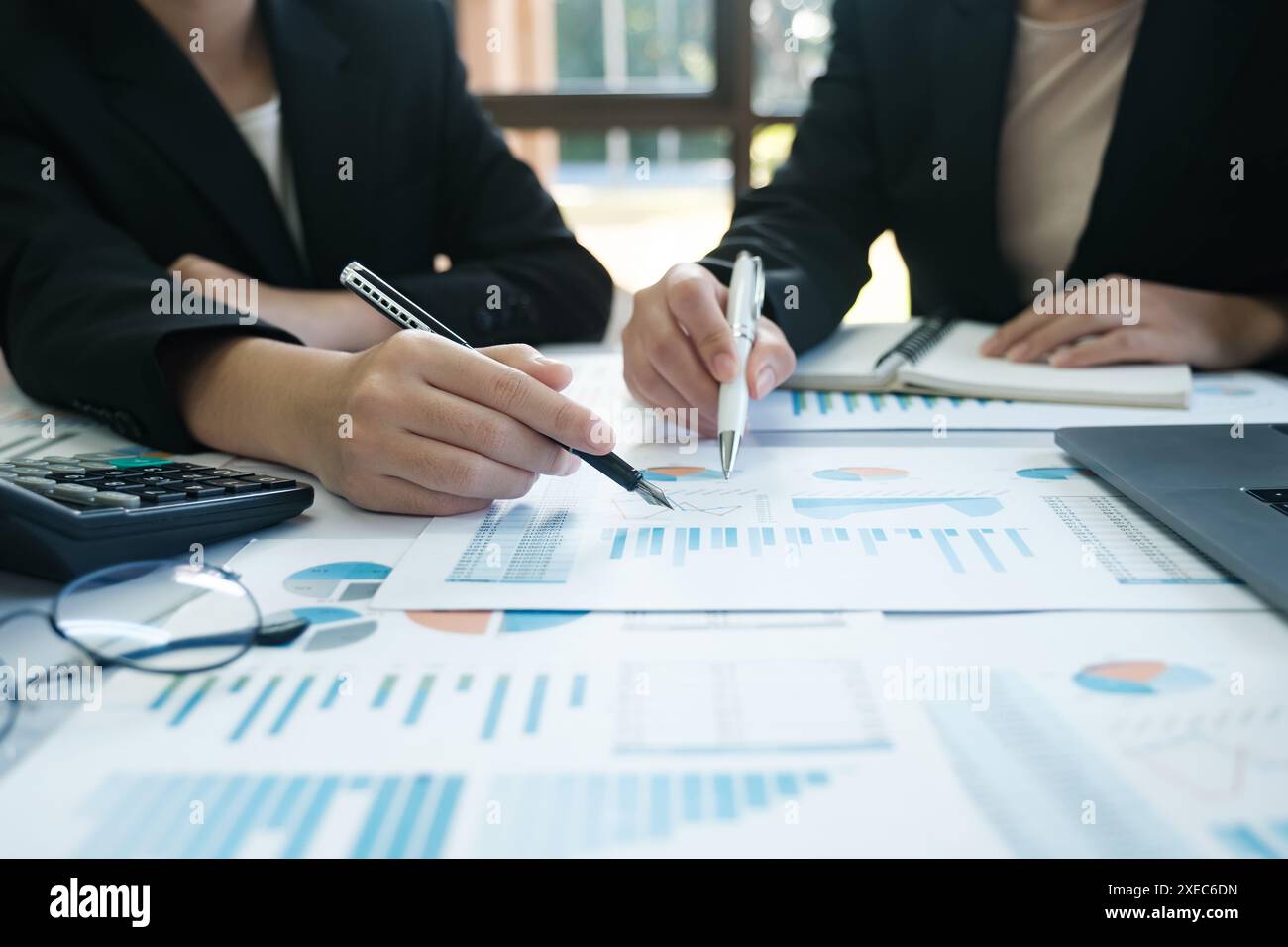 Deux femmes sont assises à une table avec beaucoup de papiers et de stylos Banque D'Images