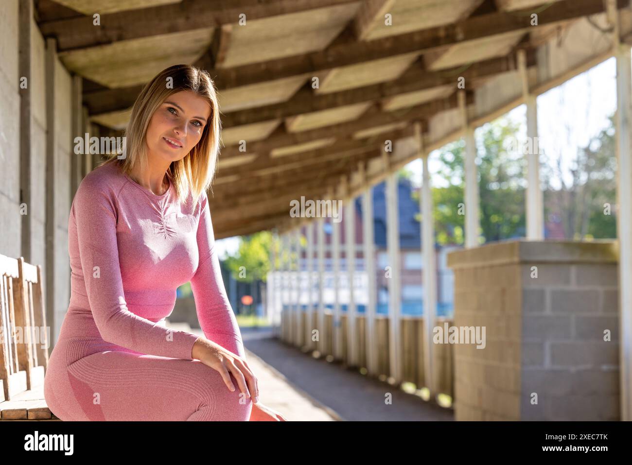 Repos athlétique : femme en Pink Sportswear profitant de la solitude urbaine Banque D'Images