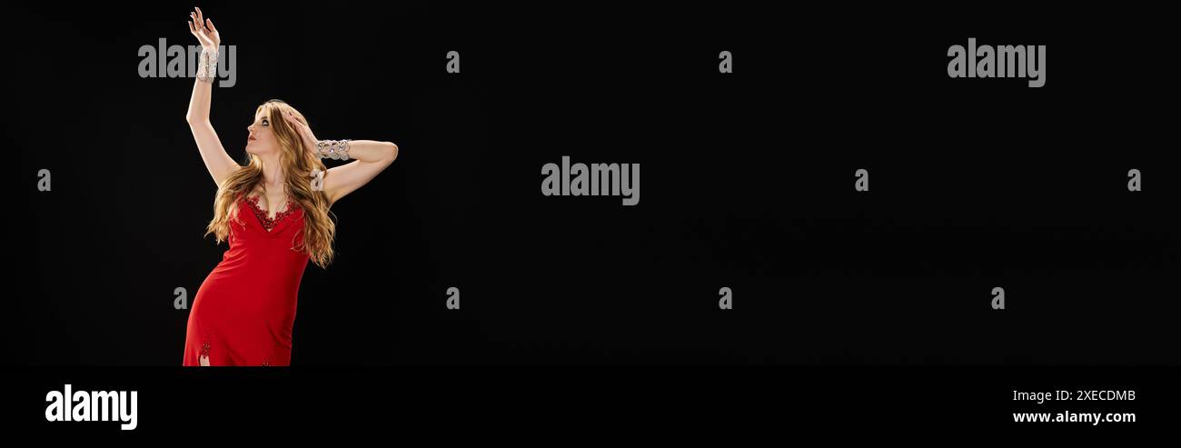 Une jeune femme vibrante danse gracieusement dans une robe rouge fluide. Banque D'Images