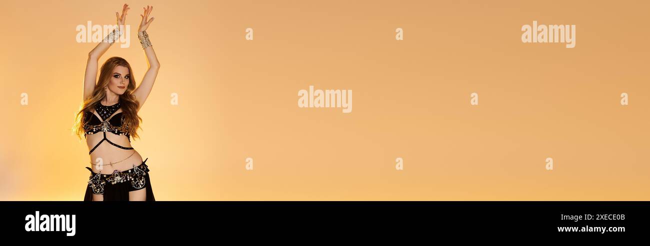 Jeune femme dans un costume noir et blanc saisissant danse gracieusement avec les bras levés. Banque D'Images