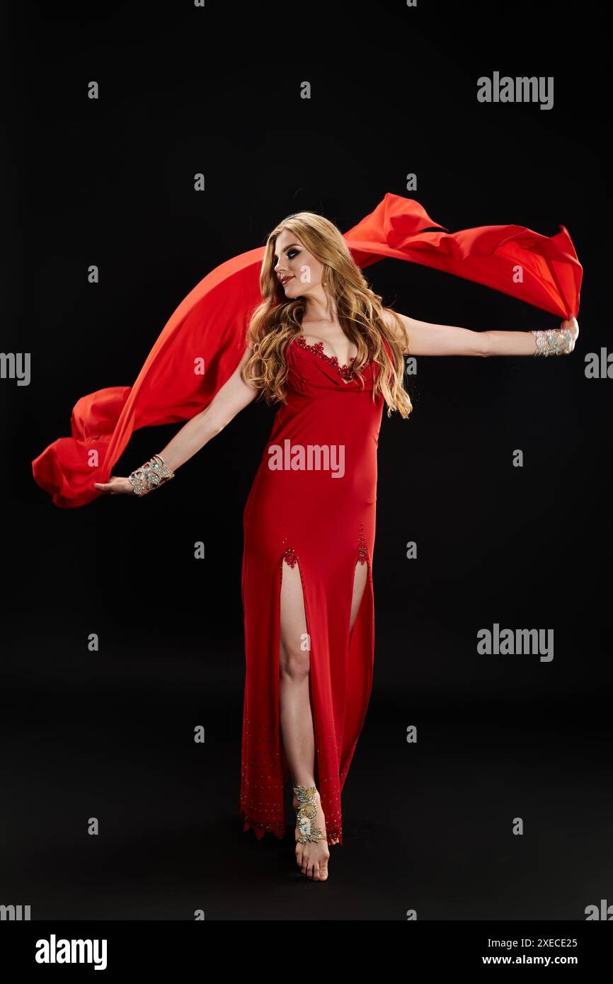 Belle femme en robe rouge danse gracieusement avec l'écharpe rouge. Banque D'Images