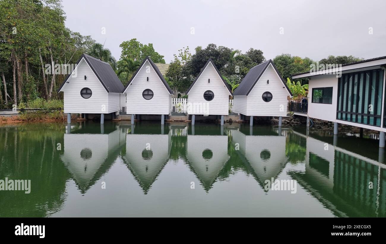 Une scène sereine avec une ligne de maisons blanches immaculées perchées gracieusement sur la surface calme d'un lac, reflétant un a rêveur Banque D'Images