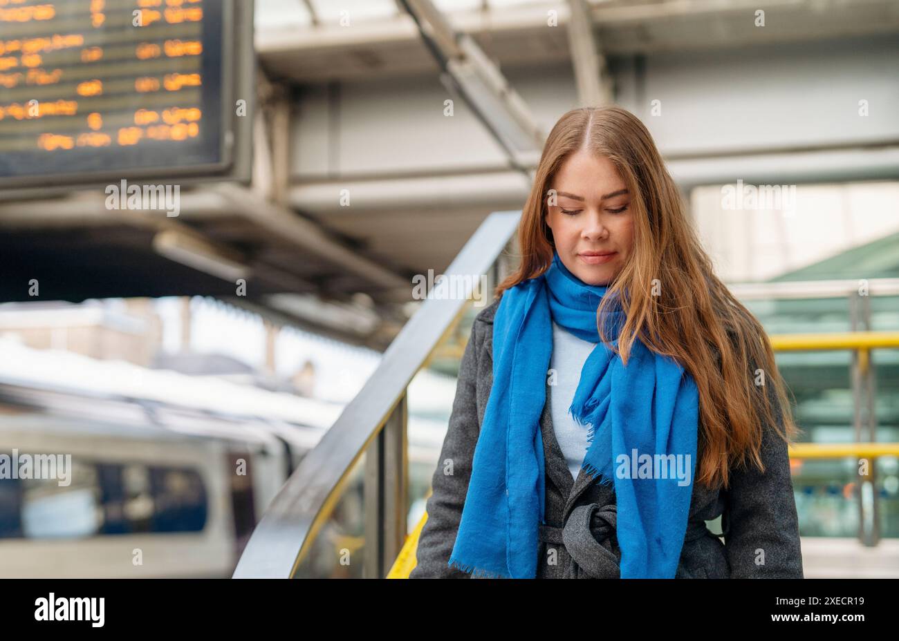 Une femme vêtue d'un manteau et d'une écharpe descendant les escaliers jusqu'au quai, attendant un train à la gare. Concept de style de vie de voyage. Banque D'Images