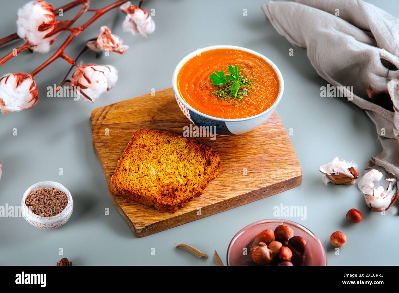 Un bol de soupe crémeuse à la tomate garni de persil, accompagné d'une tranche de pain grillé sur une planche de bois. Banque D'Images
