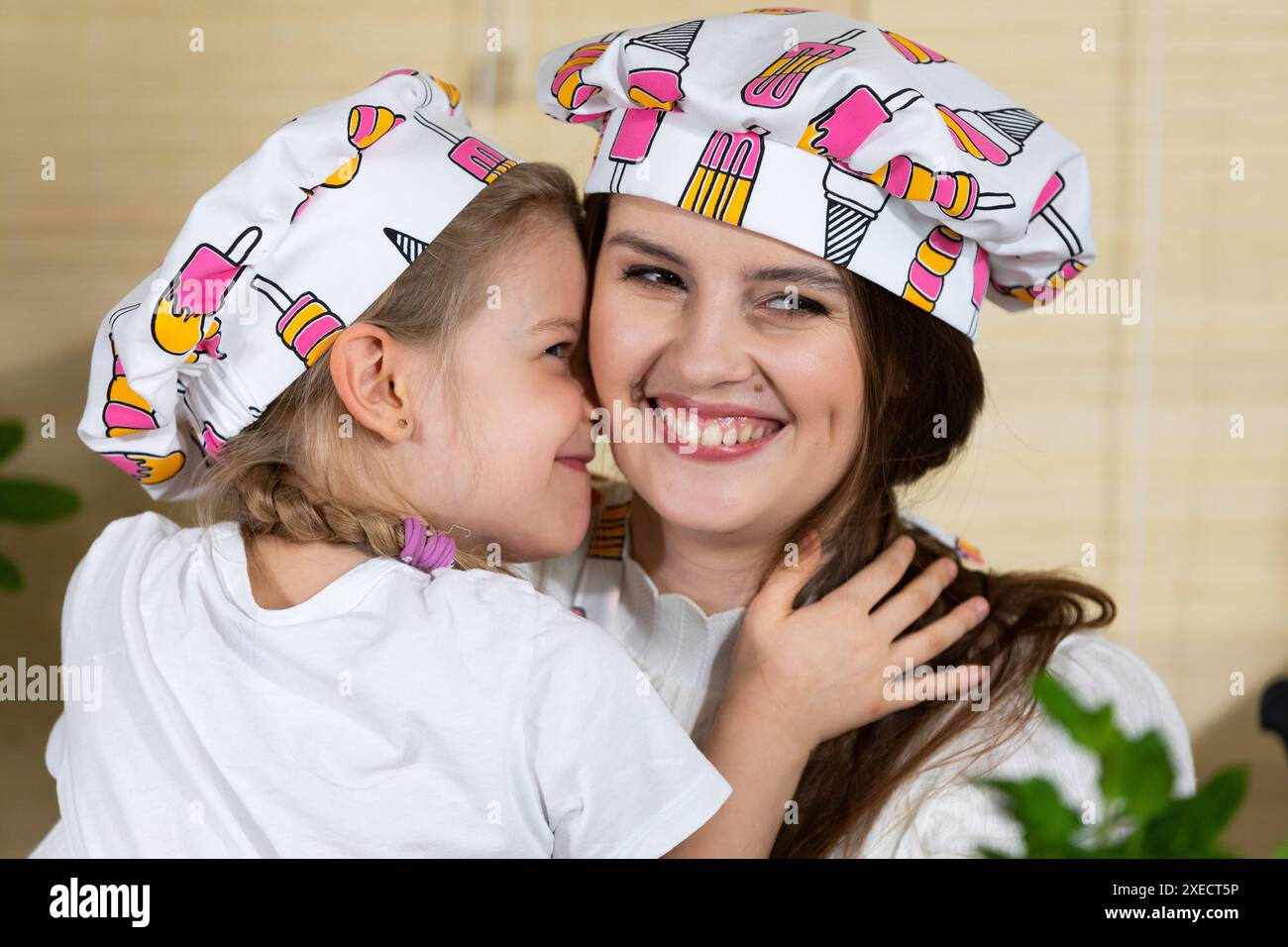 Tout en mangeant de la pizza maison, une fille de cinq ans embrasse sa mère chaleureusement, de ce fait réciproque l'amour de sa mère pour son chil Banque D'Images