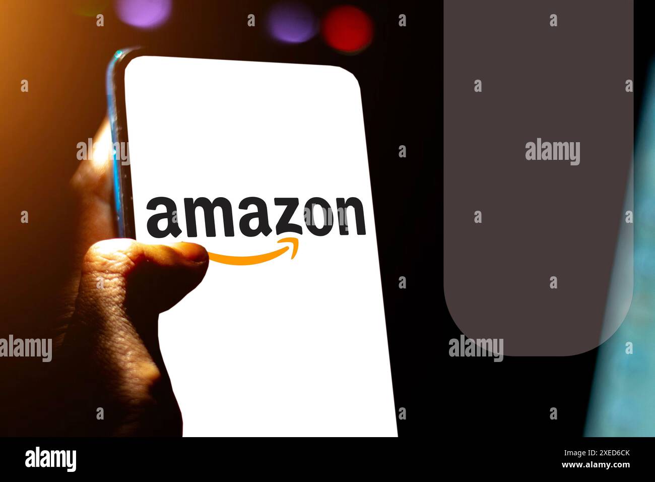 Illustration photo de la main d'un homme montrant le logo de la société Amazon sur un écran de téléphone portable. Banque D'Images