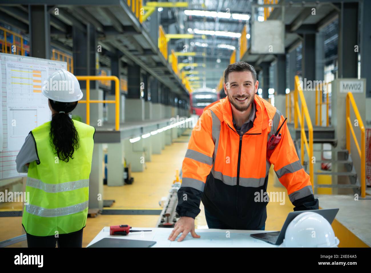 Hommes et femmes ingénieurs travaillent ensemble dans une station de réparation électrique, vérifier les détails du calendrier de réparation de train électrique. Banque D'Images