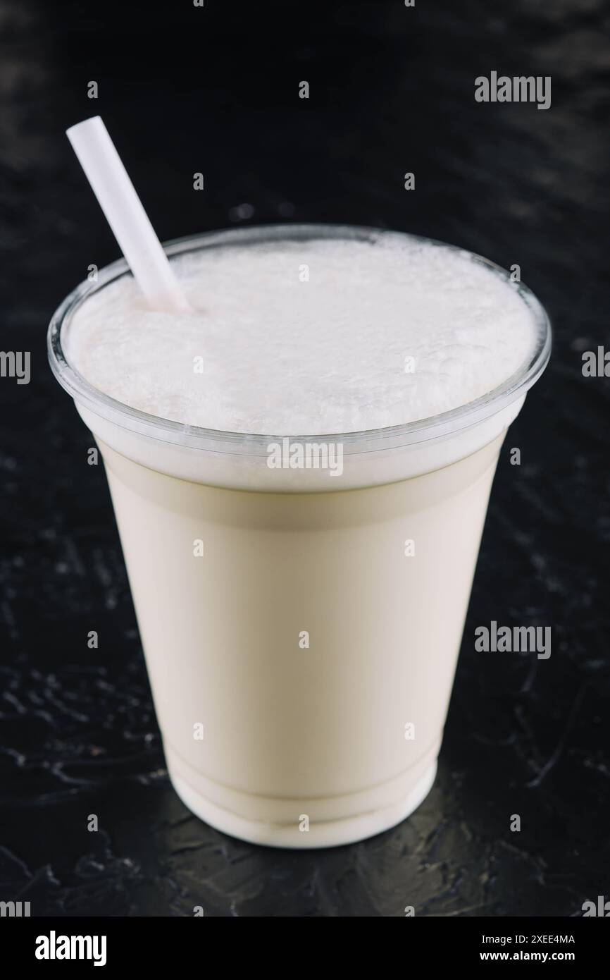 milkshake dans une tasse en plastique sur fond noir Banque D'Images