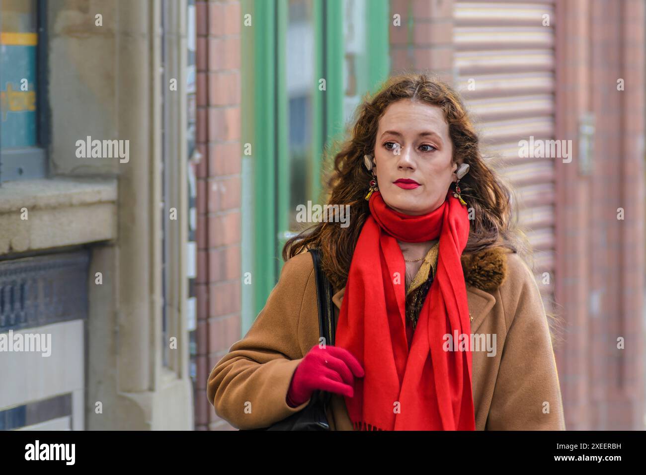 Portrait de rue captivant : femme en rouge marchant dans la rue. Dublin. Irlande. Banque D'Images