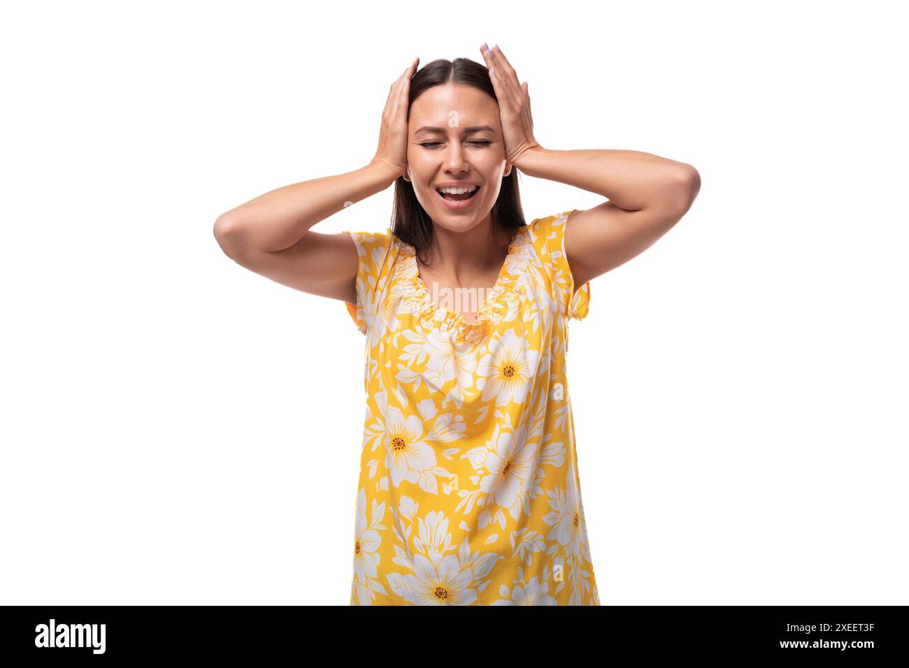 Une femme brune de 30 ans vêtue d'une tenue d'été couvrait ses oreilles et riait bruyamment Banque D'Images