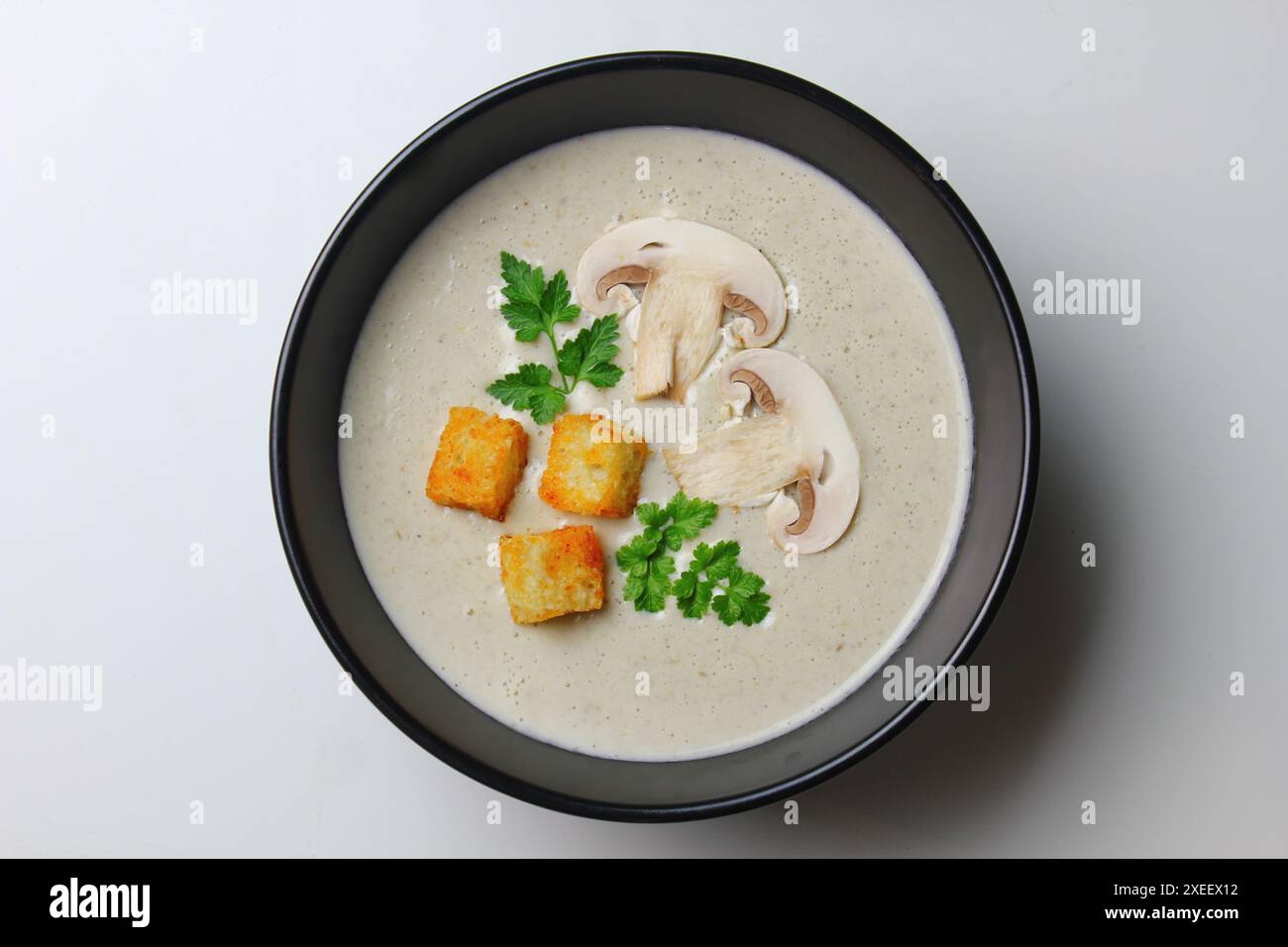 Soupe à la crème de champignons avec de la crème, des croûtons et des herbes sur un fond de bois blanc. Délicieux repas réconfortants Banque D'Images