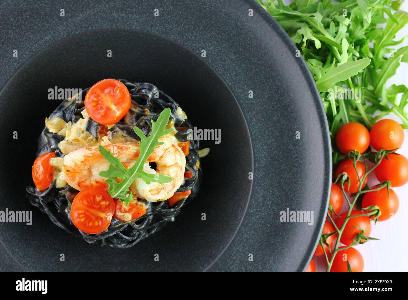 Spaghettis noirs. Pâtes de fruits de mer noires dans une assiette blanche sur fond noir avec espace de copie. Banque D'Images