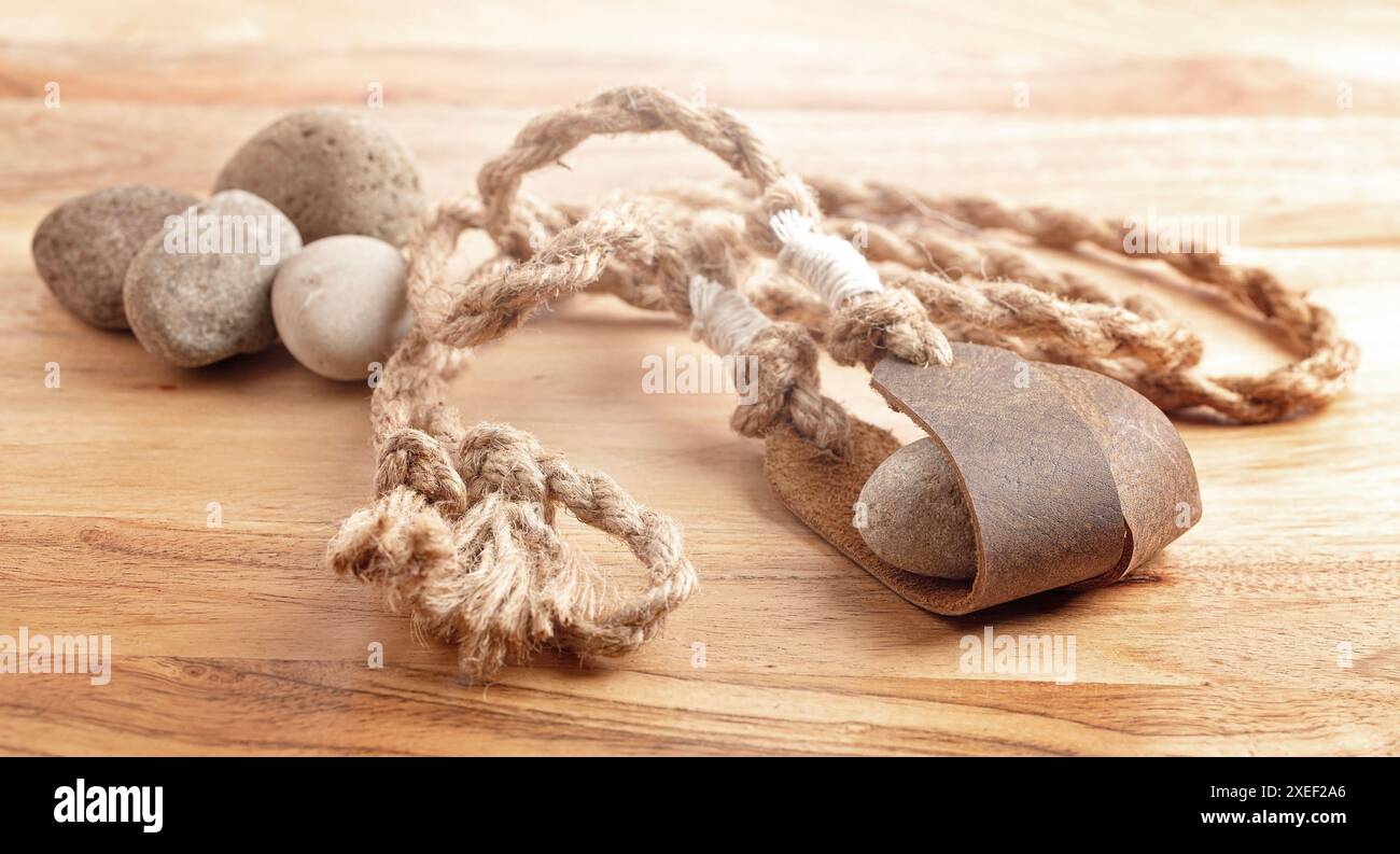 Sling Shot and Stones on a Wooden table de l'histoire de David et Goliath dans la Bible Banque D'Images