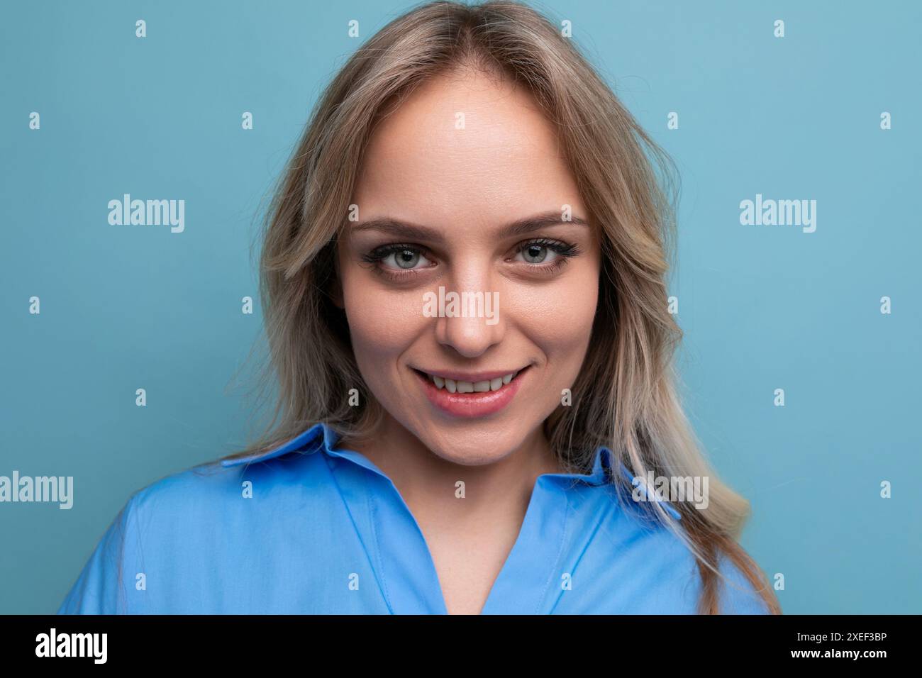 Portrait d'une adorable jeune femme blonde fermant joliment les yeux sur un fond bleu Banque D'Images