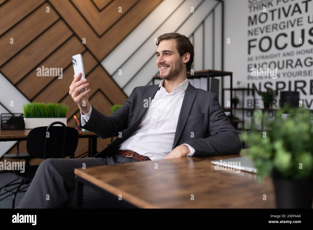 Portrait d'un joyeux financier dans le bureau vérifiant les nouvelles au téléphone Banque D'Images