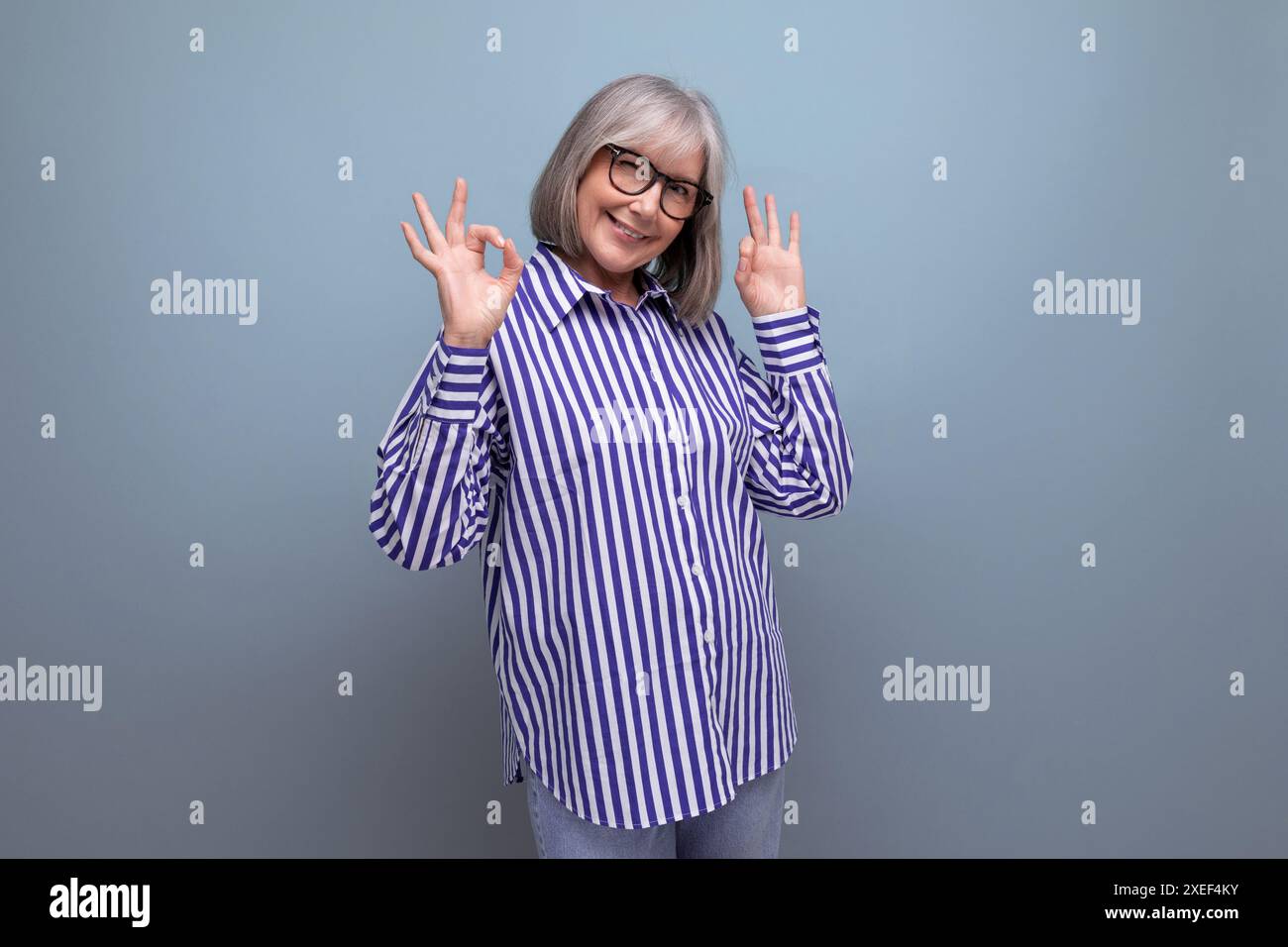 Vieille dame mature élégante dans une chemise à la mode sur un fond de studio lumineux avec copyspace Banque D'Images
