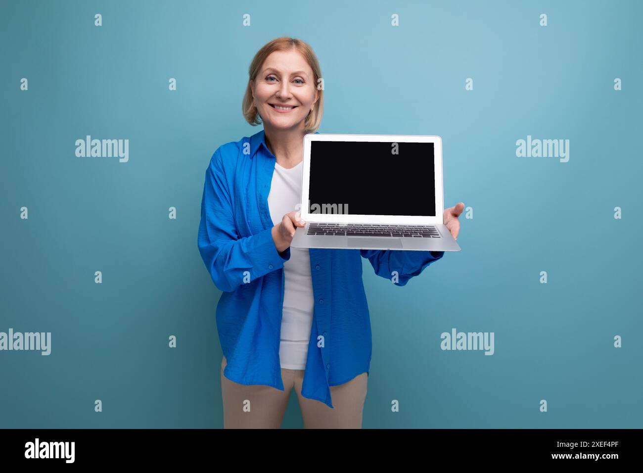Femme d'affaires adulte réussie travaillant à distance à l'aide d'un ordinateur portable sur fond bleu avec espace de copie Banque D'Images