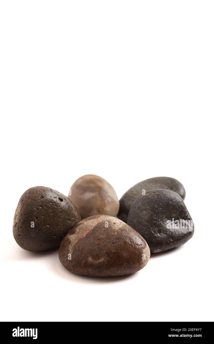 Ensemble de cinq pierres de rivière isolées sur un fond blanc semblable à l'histoire de David et Goliath Banque D'Images