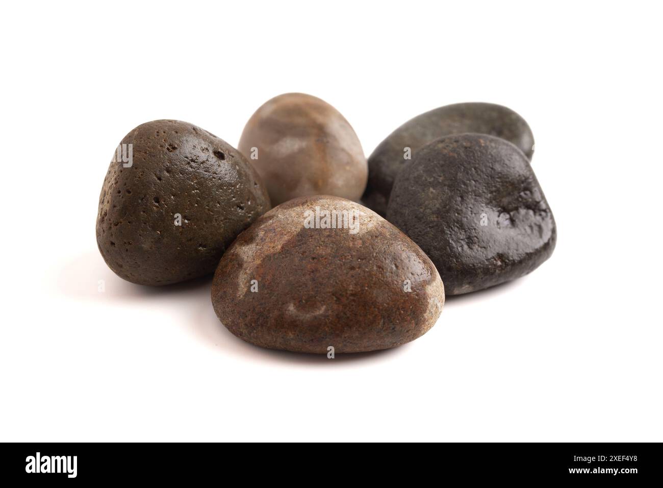 Ensemble de cinq pierres de rivière isolées sur un fond blanc semblable à l'histoire de David et Goliath Banque D'Images