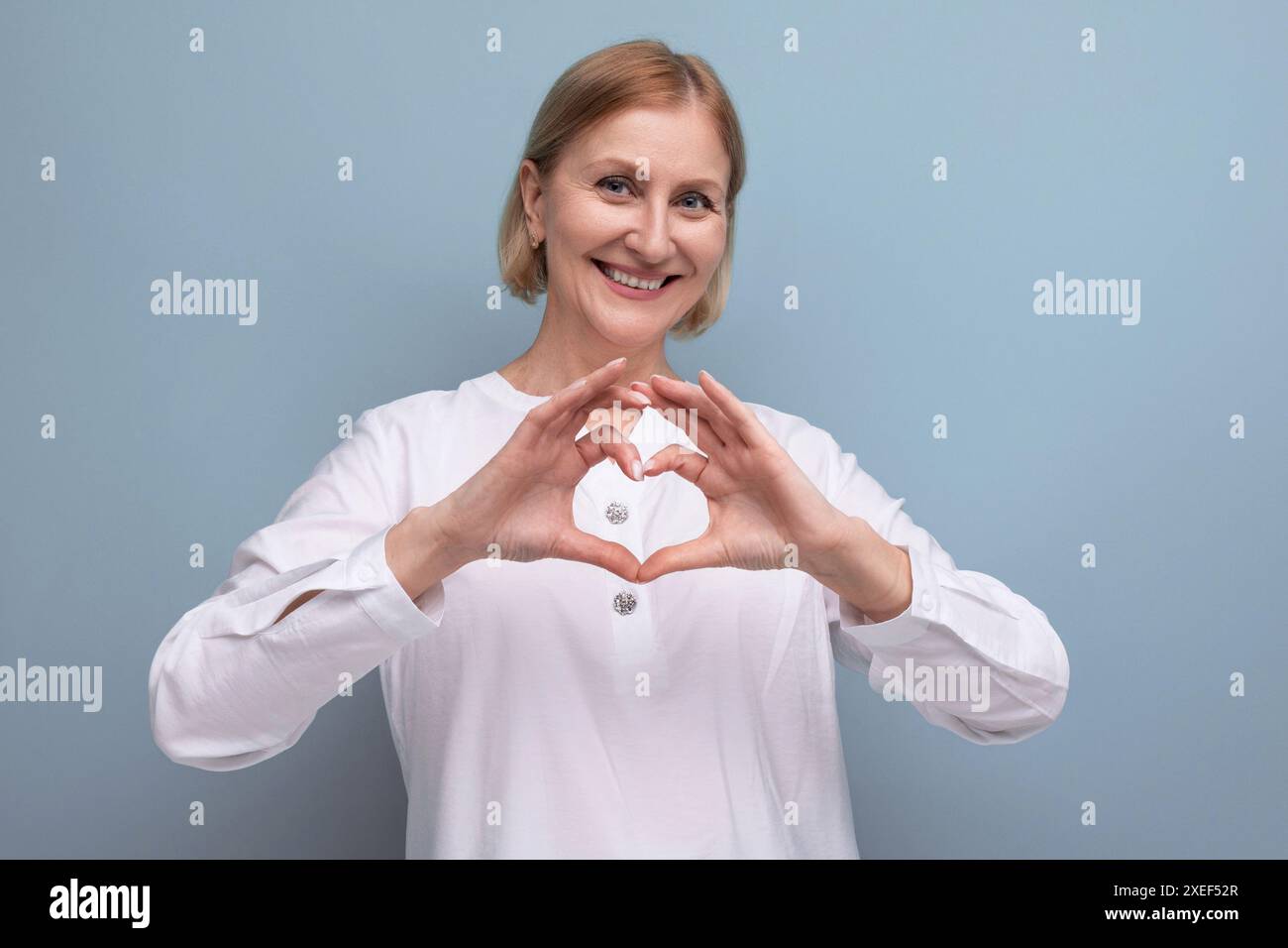 Gentille femme mature blonde agréable avec le visage propre à l'âge de ménopause en arrière-plan de studio Banque D'Images