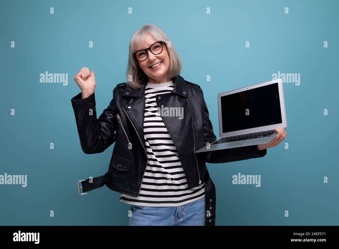 Joyeuse vieille dame mature des années 50 freelance avec les cheveux gris surfe sur Internet à l'aide d'un ordinateur portable avec maquette sur fond lumineux Banque D'Images