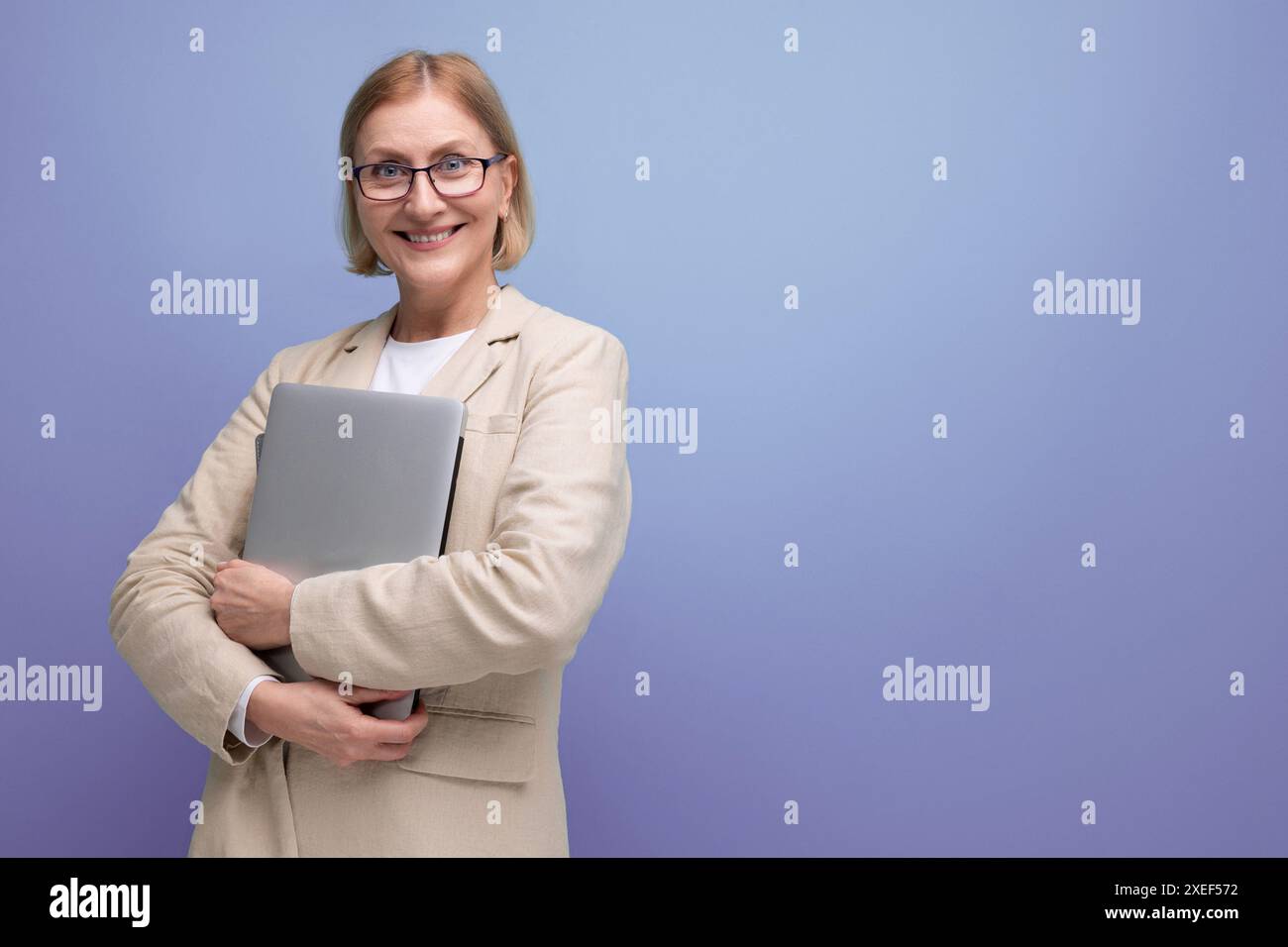 Femme mature d'âge moyen dans la veste maîtrise la nouvelle technique en utilisant un ordinateur portable sur fond de studio avec espace de copie Banque D'Images