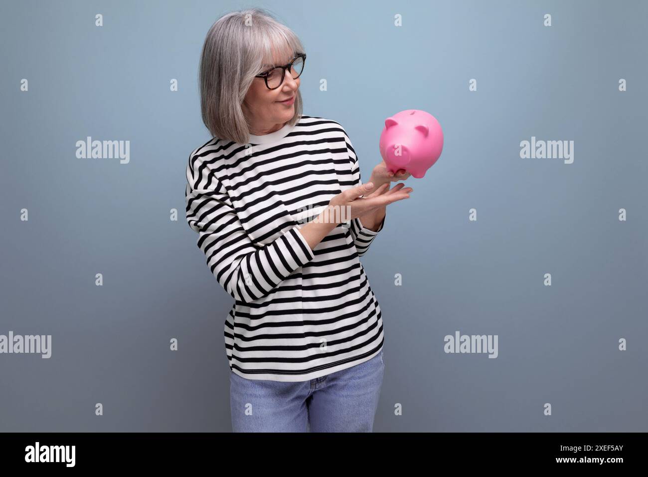 Mignonne grand-mère vieille femme des années 50 tenant une tirelire avec une pension sur un fond lumineux avec espace de copie Banque D'Images