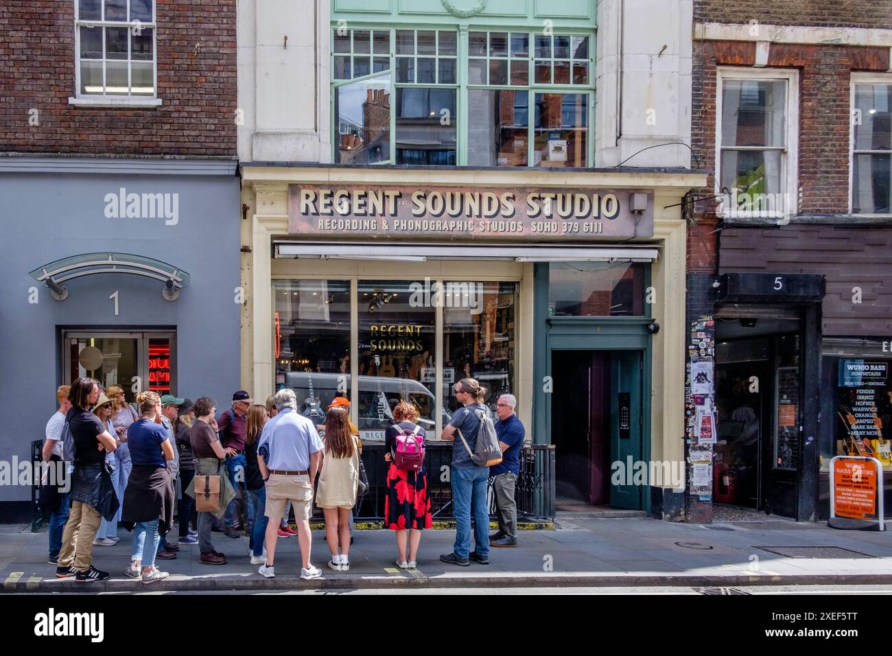 Touristes lors de la visite pédestre de musique rock londonienne dans Denmark Street, la maison traditionnelle de la scène pop britannique. Banque D'Images