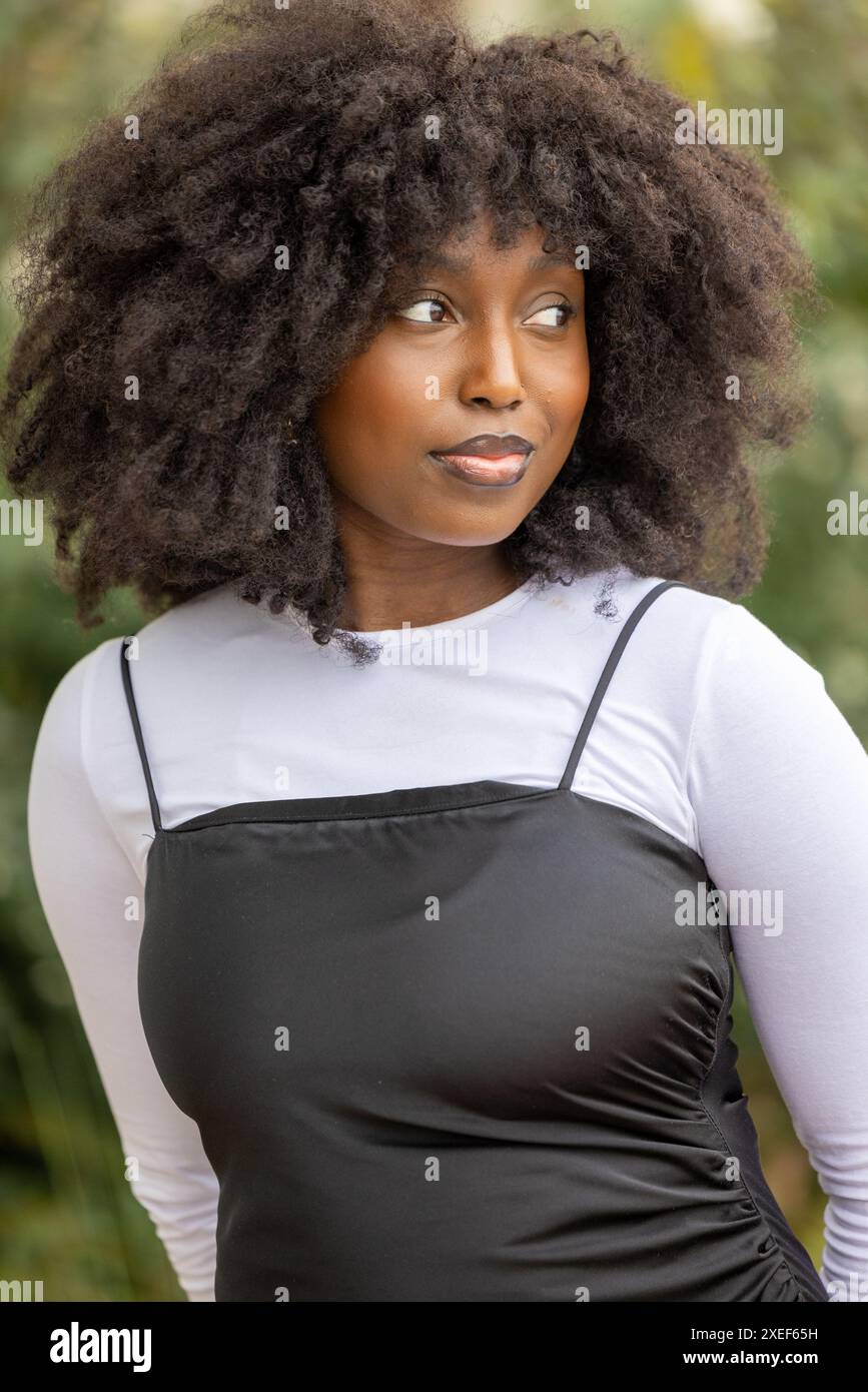 Femme noire pensive avec Afro en costume blanc et noir Banque D'Images