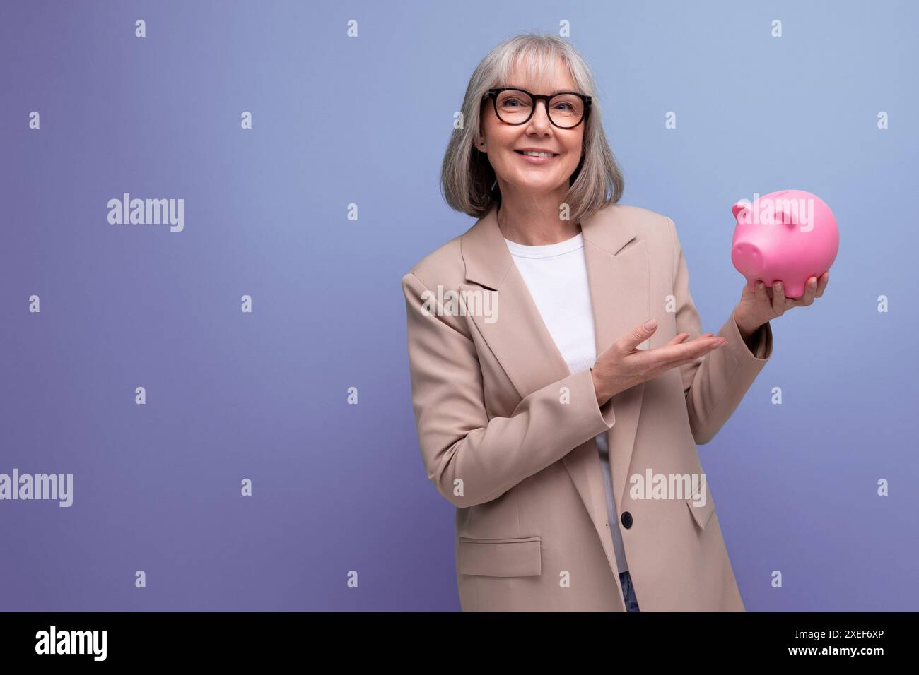 Femme d'âge moyen réussie avec une tirelire d'argent sur un fond lumineux avec espace de copie Banque D'Images
