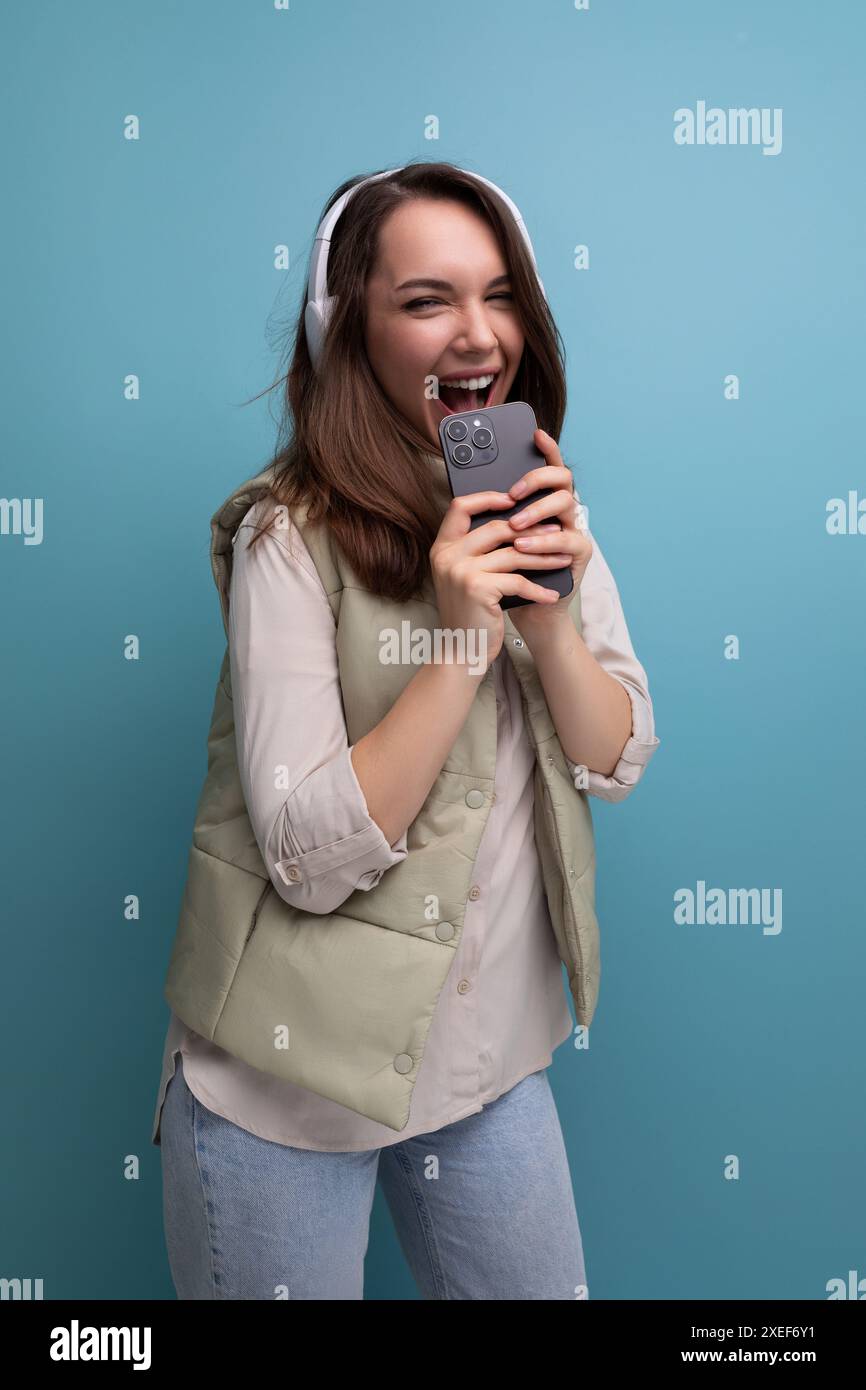 Jeune femme brune énergique se relaxant à la musique en utilisant des écouteurs et un téléphone portable Banque D'Images