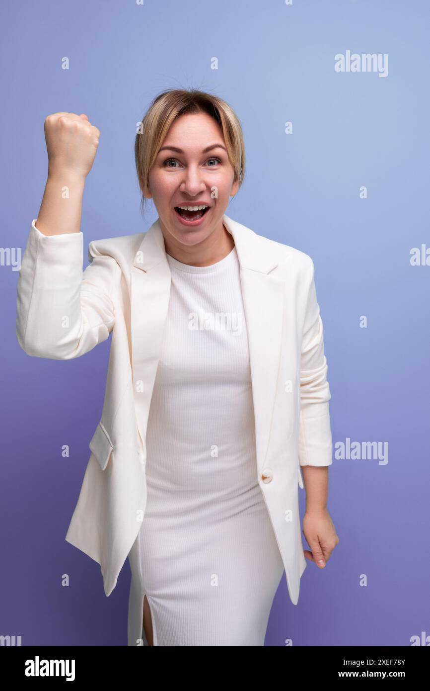 Jeune femme boss blonde joyeuse bien soignée dans une veste blanche et robe Banque D'Images