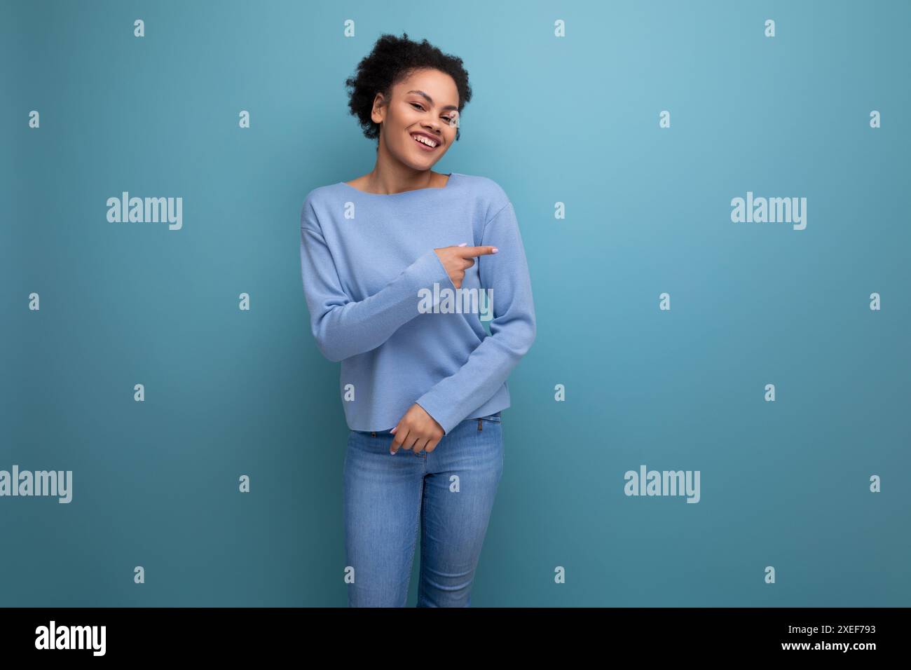 Charmante femme brune des années 20 avec boucles afro dans des vêtements décontractés élégants isolés avec fond de studio Banque D'Images