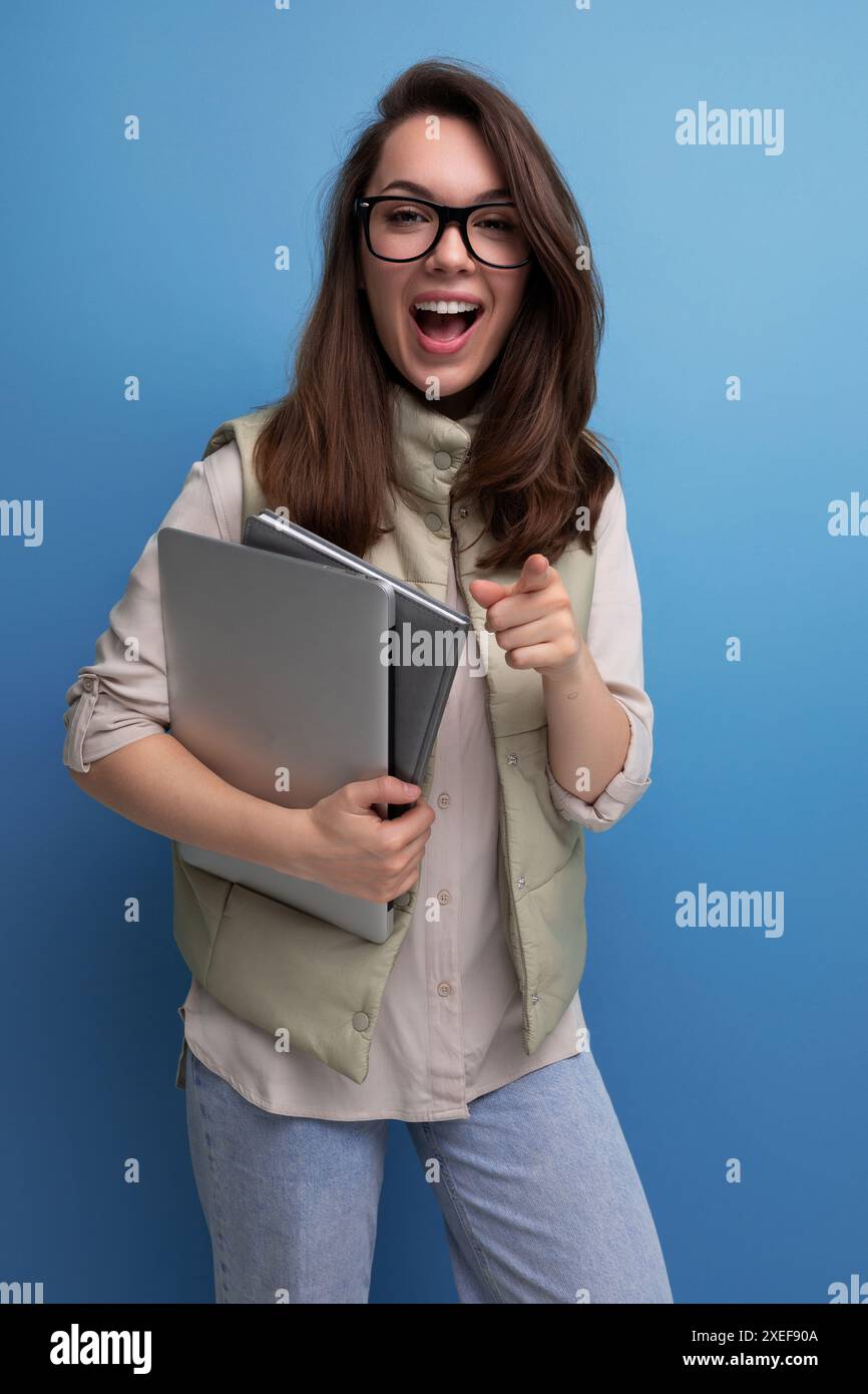 Étudiante positive des années 30 tenant des documents et un ordinateur portable sur fond d'espace vide Banque D'Images