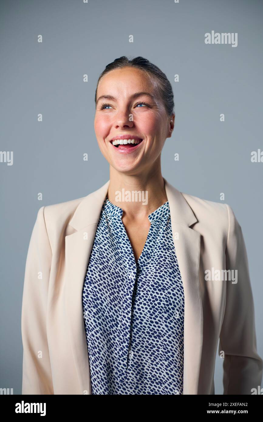 Studio Portrait de femme d'affaires souriante portant costume sur fond gris Banque D'Images