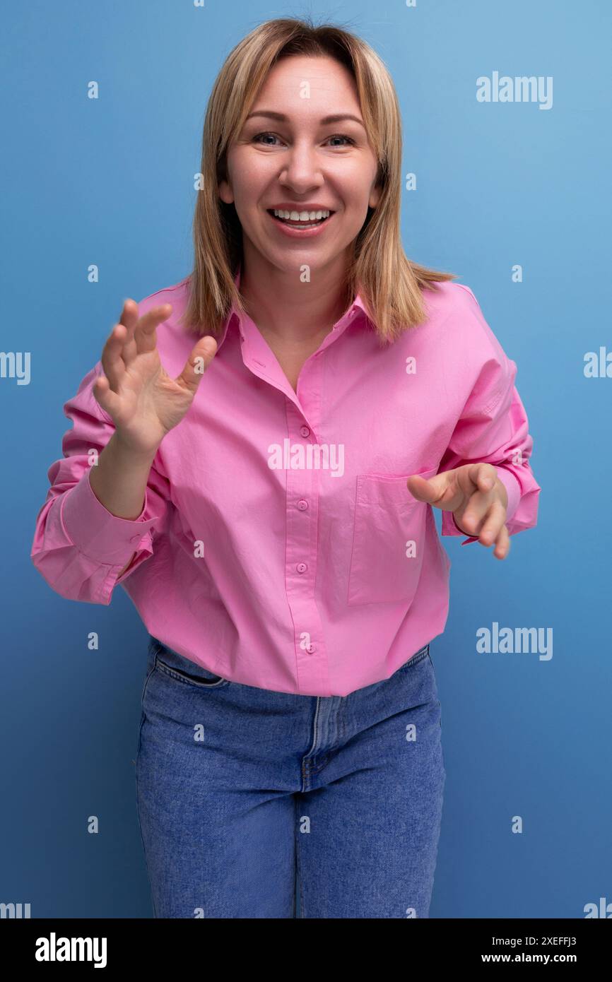 Jeune jolie femme de bureau européenne blonde avec les cheveux coulants dans une blouse rose sourit doucement Banque D'Images
