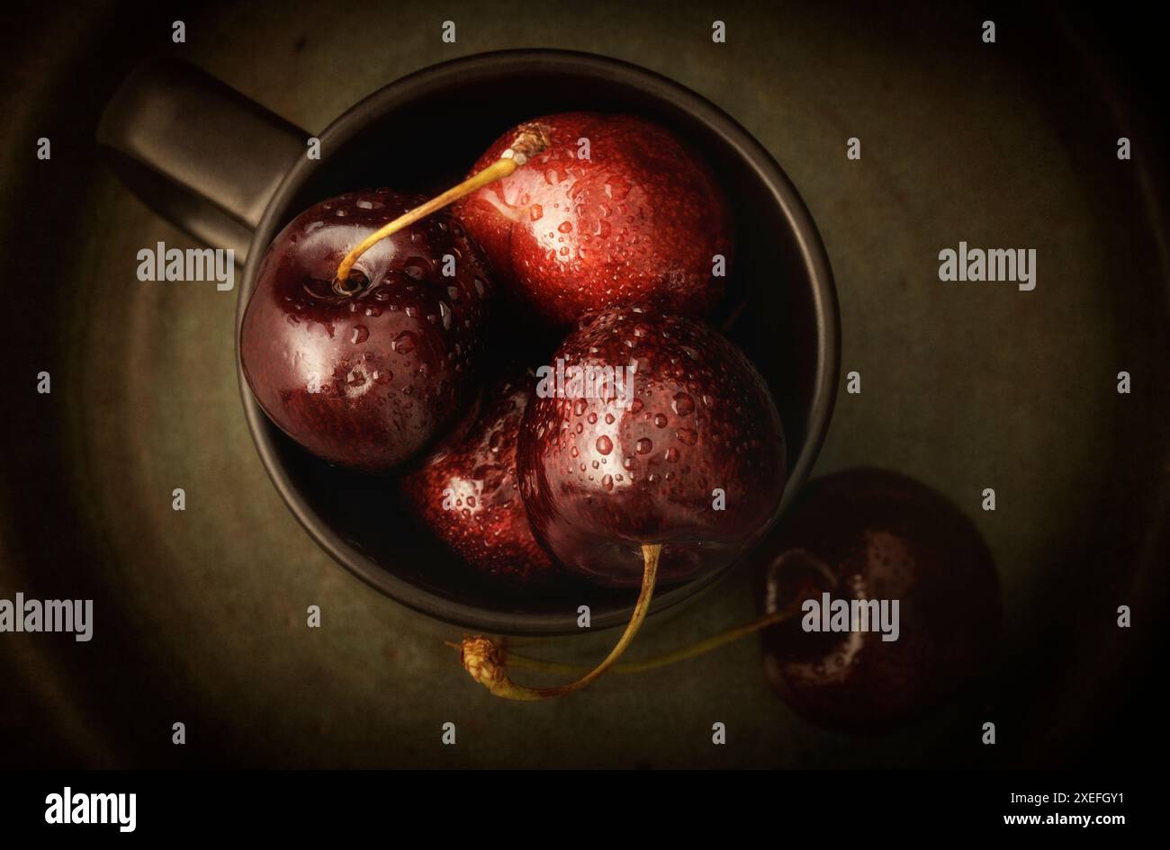 Cerises fraîches dans une tasse noire gros plan Banque D'Images