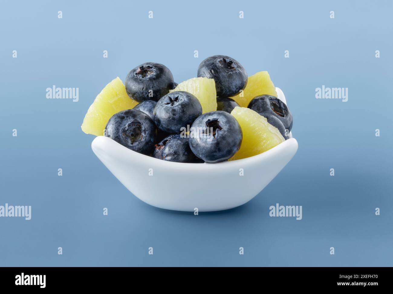 Bol blanc avec des baies bleues fraîches et des morceaux d'ananas Banque D'Images