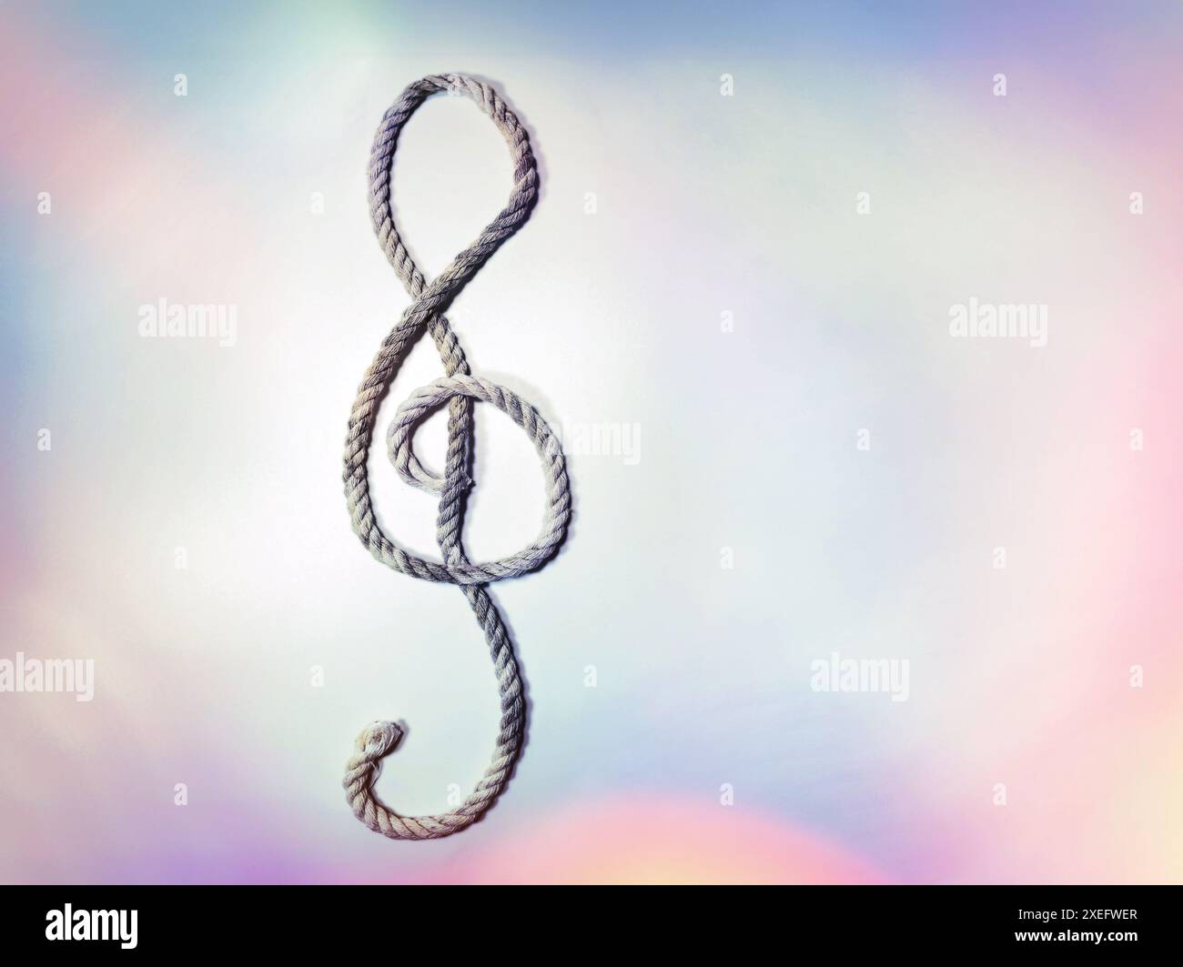 Corde grossière posée sous la forme d'une clef d'aigu ou d'une clef de violon sur un fond pastel chatoyant, symbole musical, espace de copie, foyer sélectionné Banque D'Images