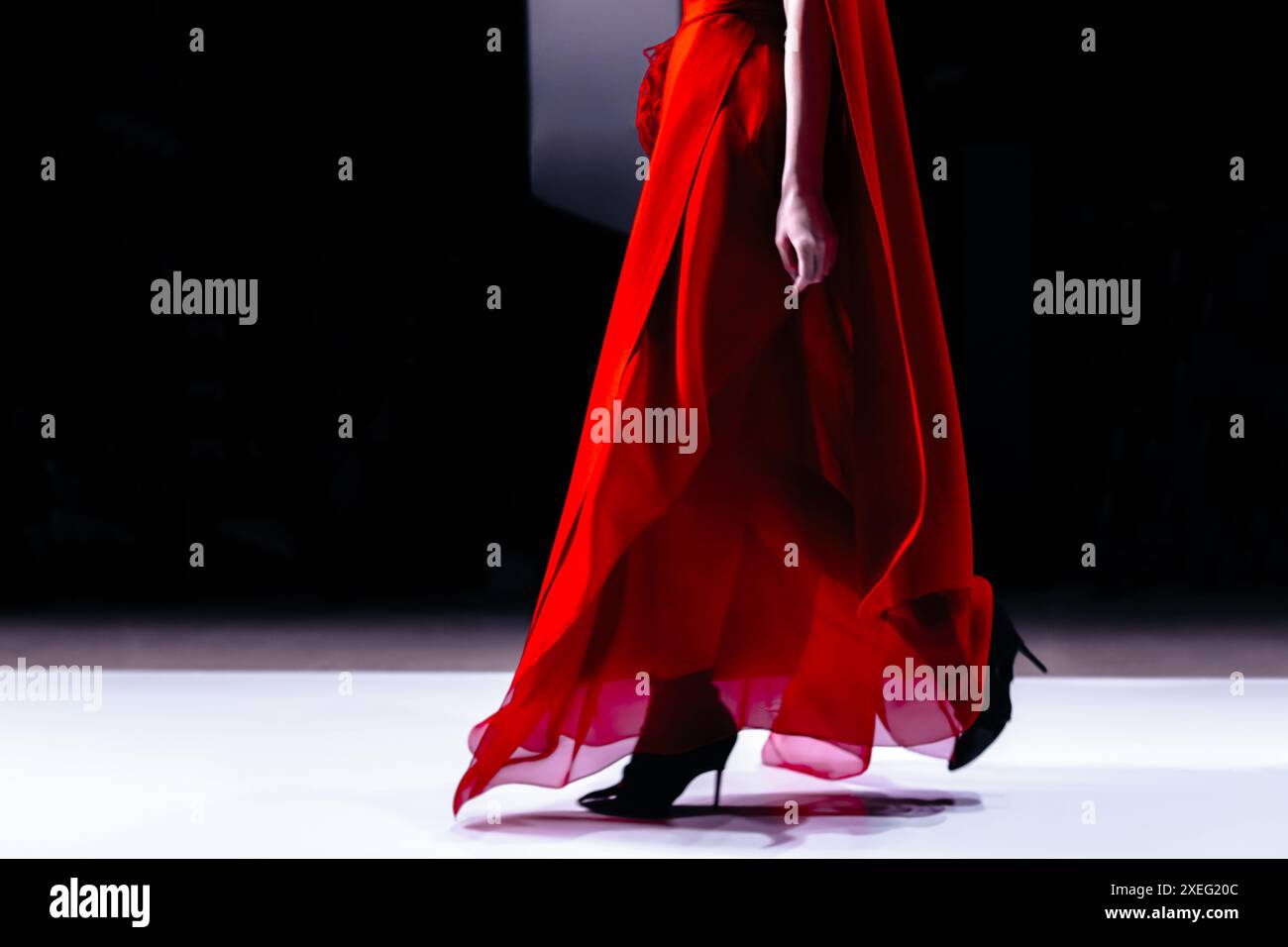 Élégante robe rouge vif élégante sur une figure féminine et chaussures à talons hauts, vêtements et tenue élégants sur fond noir Banque D'Images