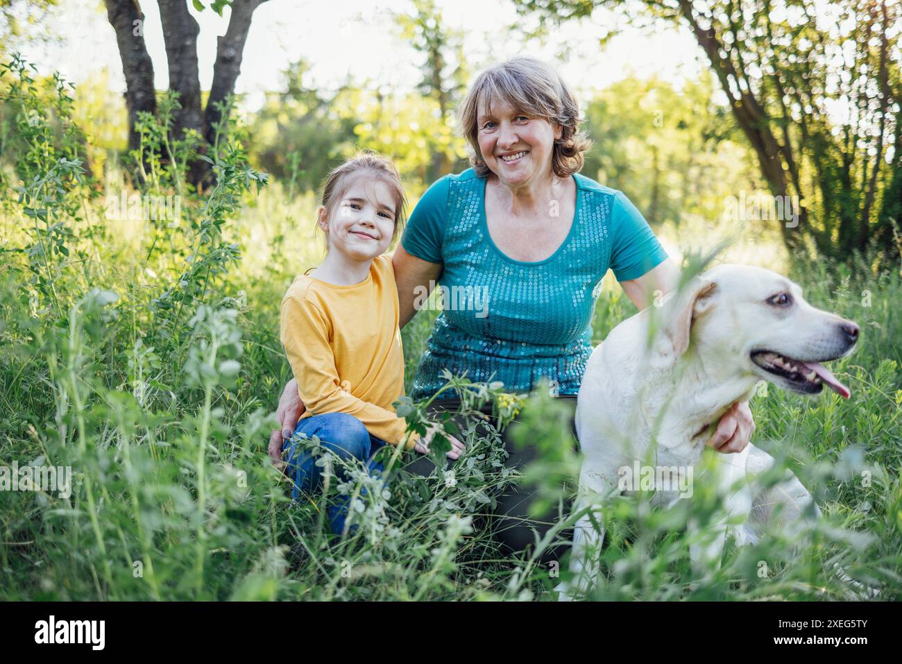 Grand-mère aux cheveux gris et petite-fille mignonne promènent leurs chiens ensemble dans le parc Banque D'Images