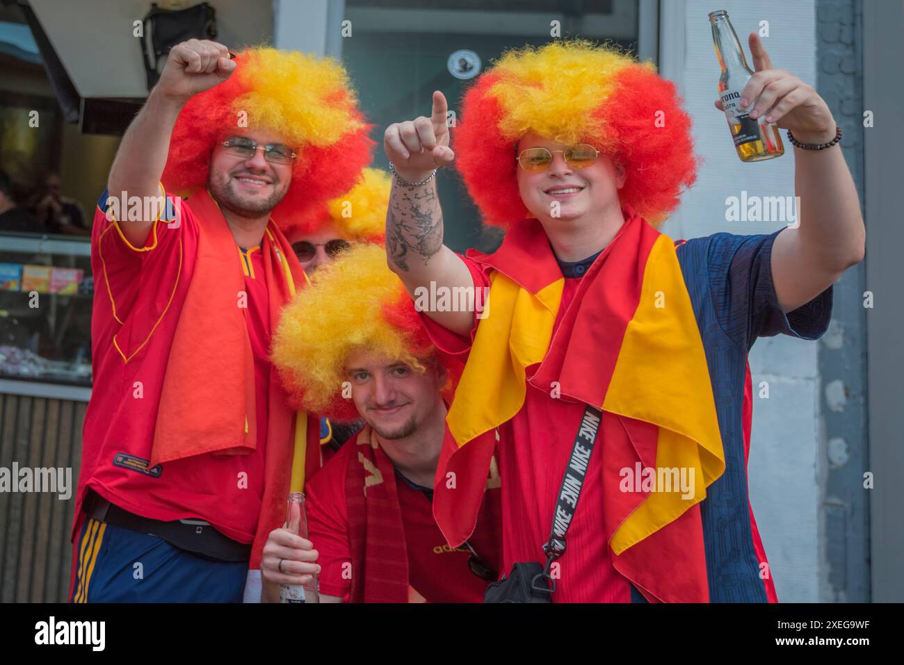 Quatre fans de football espagnols vêtus de rouge et jaune avec des perruques rouge-jaune, célèbrent dans la vieille ville de Düsseldorf pendant l'EURO 2024 Banque D'Images