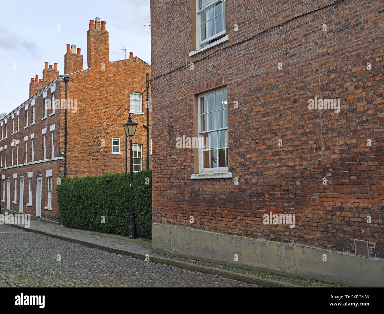 Rue de vieilles maisons géorgiennes traditionnelles en briques rouges sur une route pavée à Chester en Angleterre Banque D'Images