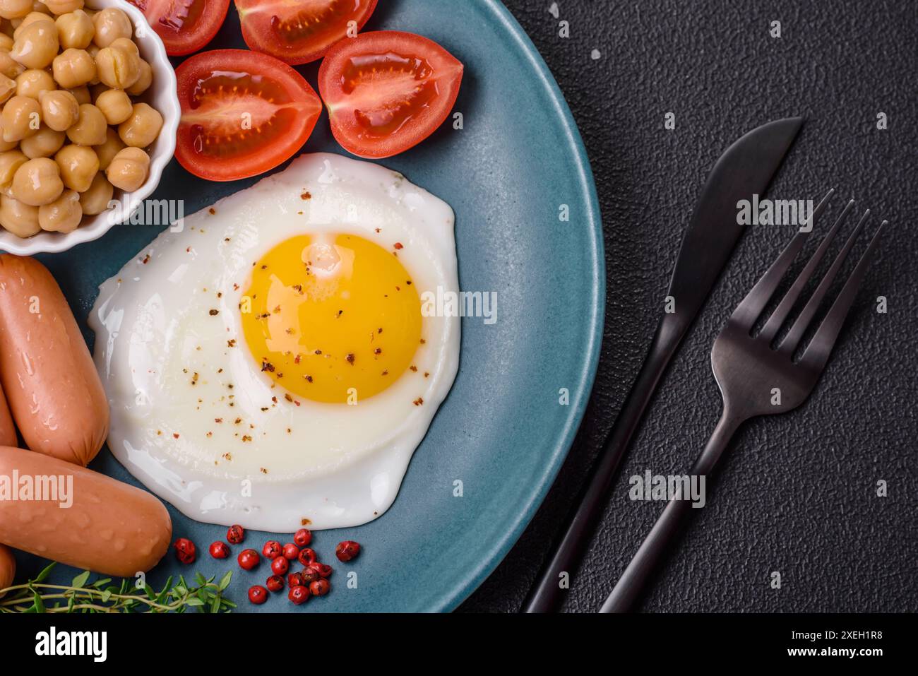 Œufs de poule frits, saucisses, tomates cerises, pois chiches, épices, sel et herbes Banque D'Images