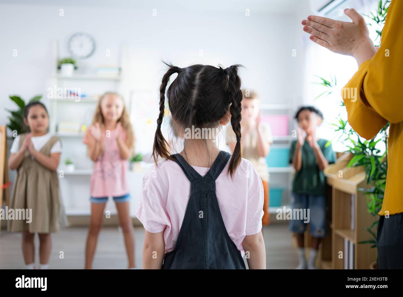 Enseignant et élèves, applaudissements pour féliciter un élève de la classe. Banque D'Images