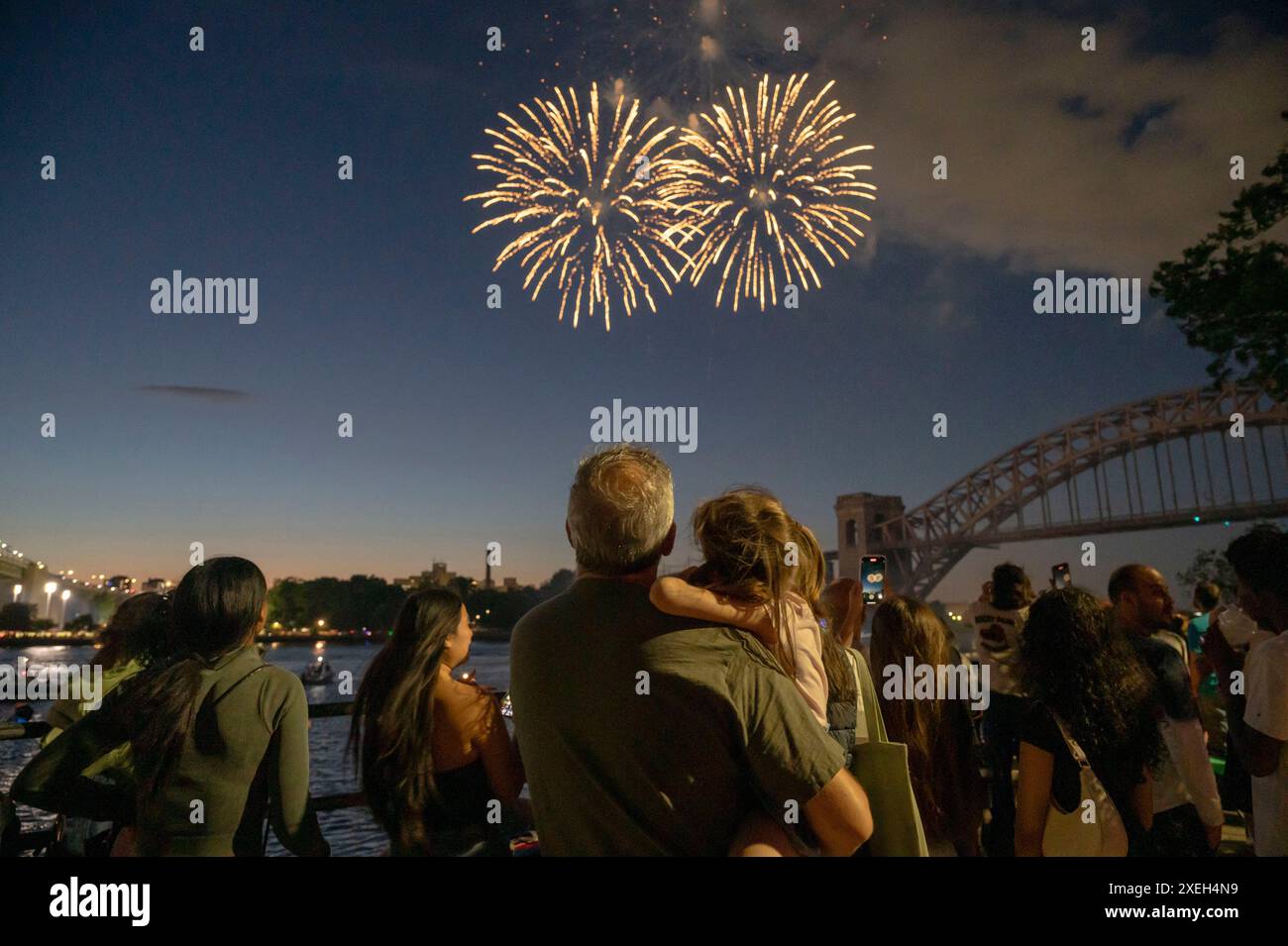 New York, États-Unis. 27 juin 2024. NEW YORK, NEW YORK - JUIN 27 : une enfant assise sur les épaules de son père regarde des feux d'artifice exploser pendant le spectacle annuel des célébrations du jour de l'indépendance de Central Astoria à Astoria Park le 27 juin 2024 dans le Queens borough de New York. Crédit : Ron Adar/Alamy Live News Banque D'Images