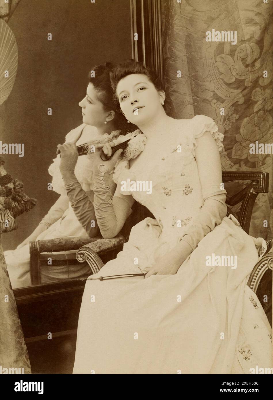 1890 CA, Paris, FRANCE : L'actrice de théâtre française Mademoiselle DARCELLE . Du Théâtre des Nouveautés était aussi une star d'Operetta et est considérée comme l'une des plus belles femmes de Paris. Son plus grand succès a été réalisé à L'amour mouillé en 1885. Photo de NADAR , Paris. - HISTOIRE - FOTO STORICHE - attrice - TEATRO -THEATRE - DIVA - DIVINA - BELLE EPOQUE - MIROIR - REFLEX - SPECCHIO - RIFLESSO - boucle d'oreille perles - Orecchino di perla - decolleté - scollatura - CANTANTE - MUSIQUE - MUSICA - gants - guanti - robe blanche - abito vestito bianco - ventilateur - ventaglio - MODE - MODA FEMME - OTTO Banque D'Images